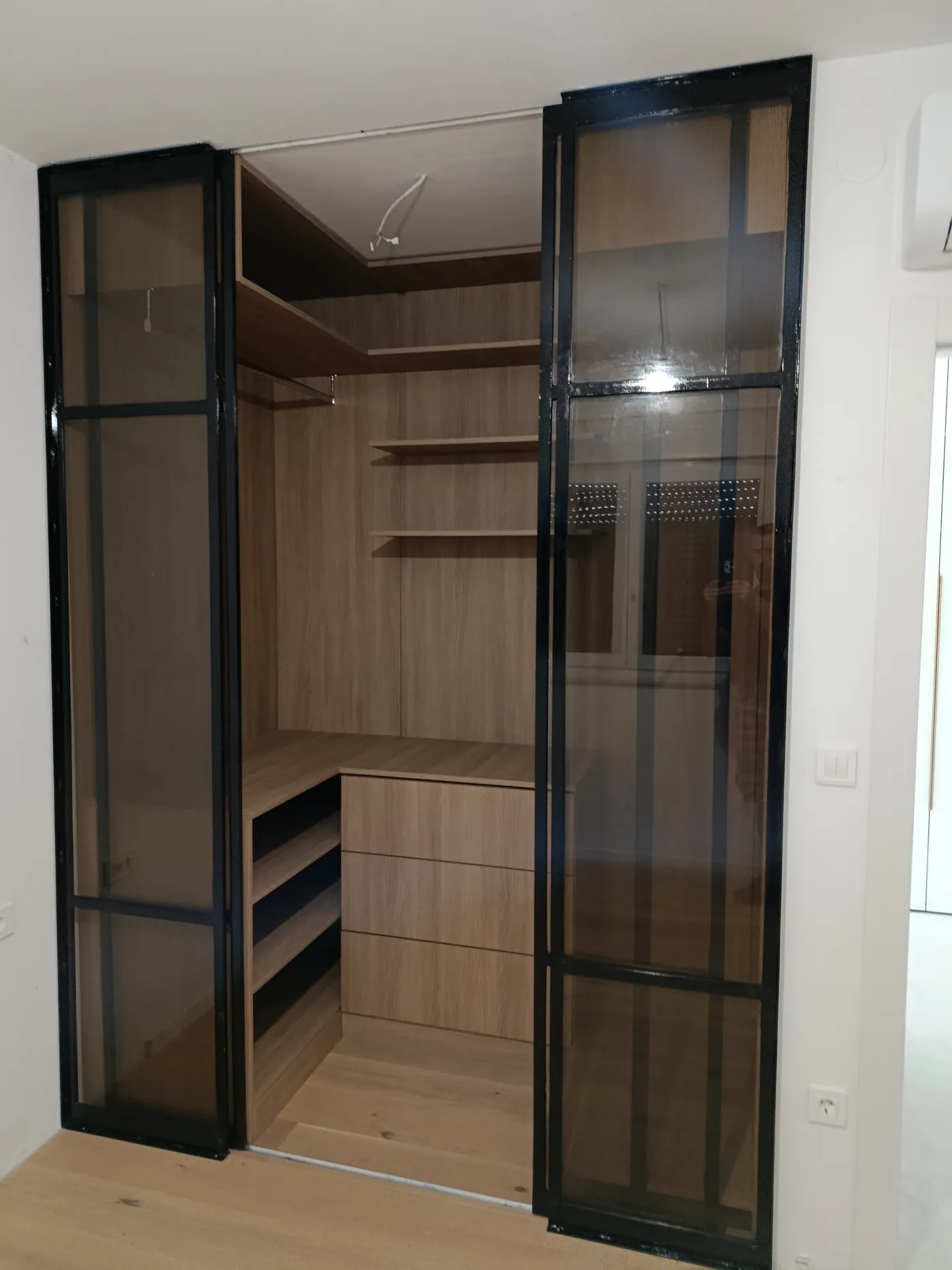 Unutrašnjost walk-in garderobe u orahu, snimljena kroz staklena klizna vrata